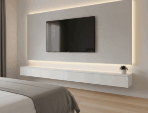 A modern bedroom media wall featuring a wall-mounted floating TV above a sleek white floating console with hidden drawers, illuminated by warm LED backlighting, with a bed in the foreground.
