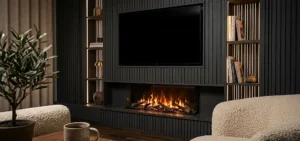 A cozy living room with a dark slatted feature wall, an electric fireplace, a large TV, and lit bookshelves.